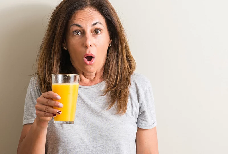 Surprised woman drinking orange juice